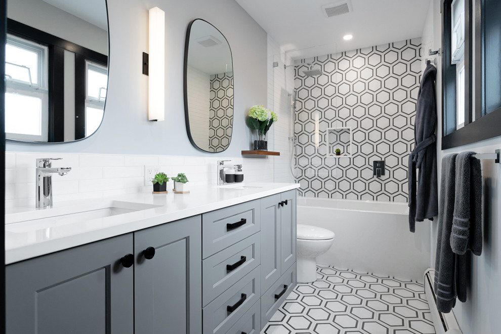 This is an example of a large transitional master bathroom in Vancouver with grey cabinets, an alcove tub, a shower/bathtub combo, grey walls, an undermount sink, white benchtops, a niche, a double vanity, a built-in vanity, shaker cabinets, a one-piece toilet, gray tile, porcelain floors, engineered quartz benchtops, white floor and an open shower.
