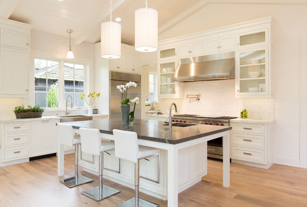 Inspiration for a large traditional l-shaped open plan kitchen in San Francisco with a farmhouse sink, shaker cabinets, white cabinets, granite benchtops, white splashback, subway tile splashback, stainless steel appliances, medium hardwood floors and with island.