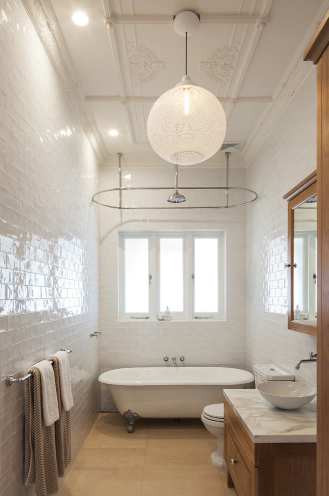 This is an example of a scandinavian bathroom in Sydney with marble benchtops, a claw-foot tub, a shower/bathtub combo, a one-piece toilet, white tile, ceramic tile and light hardwood floors.