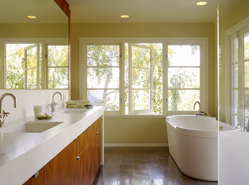 Inspiration for a small modern master bathroom in San Francisco with flat-panel cabinets, medium wood cabinets, a freestanding tub, a one-piece toilet, brown tile, stone slab, green walls, light hardwood floors, an undermount sink and limestone benchtops.