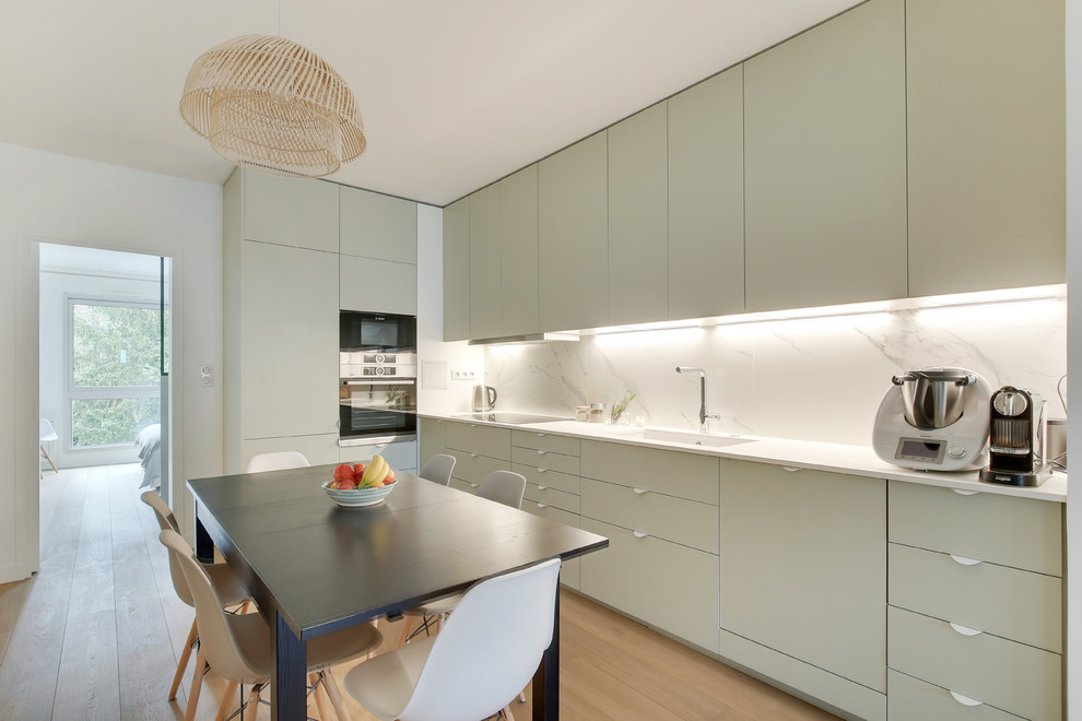 Design ideas for a scandinavian eat-in kitchen in Paris with a single-bowl sink, flat-panel cabinets, grey cabinets, white splashback, marble splashback, light hardwood floors, beige floor and white benchtop.