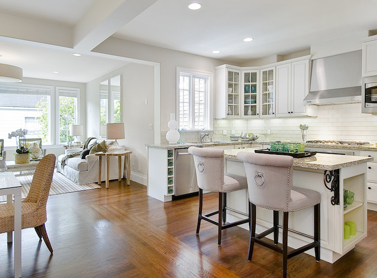 Example of a mid-sized transitional u-shaped medium tone wood floor and brown floor open concept kitchen design in Austin with an undermount sink, raised-panel cabinets, white cabinets, granite countertops, white backsplash, subway tile backsplash, stainless steel appliances, an island and beige countertops