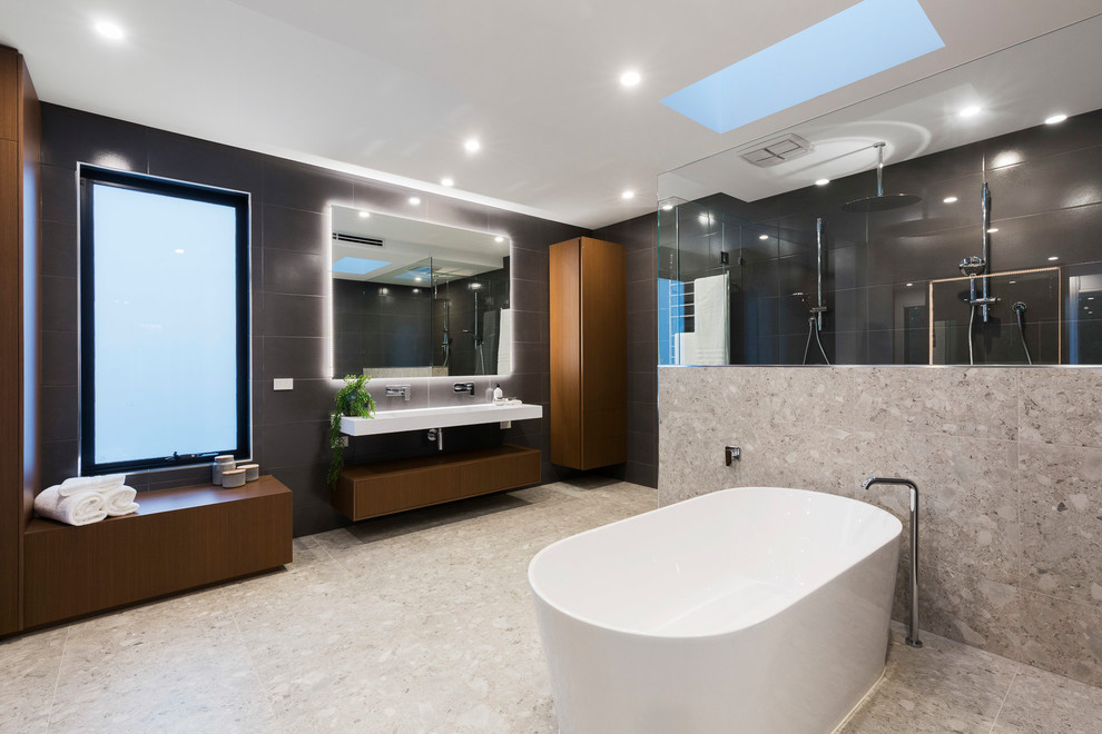Contemporary master bathroom in Melbourne with flat-panel cabinets, dark wood cabinets, a freestanding tub, a double shower, black tile, gray tile, black walls, grey floor and white benchtops.