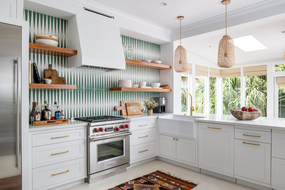 Example of a transitional beige floor kitchen design in Houston with a farmhouse sink, shaker cabinets, white cabinets, gray backsplash, stainless steel appliances, a peninsula and white countertops