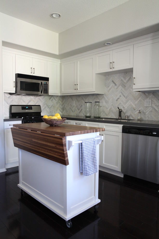 Open concept kitchen - small transitional l-shaped dark wood floor open concept kitchen idea in Orange County with a drop-in sink, shaker cabinets, white cabinets, quartzite countertops, white backsplash, stone tile backsplash, stainless steel appliances and an island