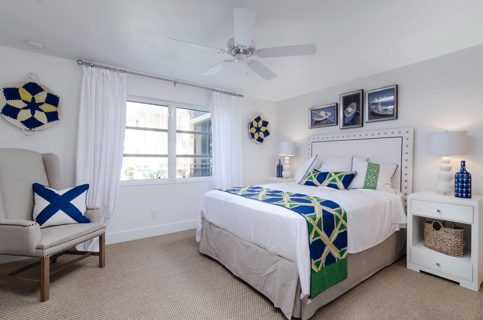 Large beach style guest bedroom in Miami with white walls, carpet, beige floor and no fireplace.