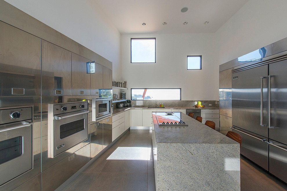 Design ideas for a mid-sized contemporary separate kitchen in Other with an undermount sink, flat-panel cabinets, stainless steel cabinets, granite benchtops, white splashback, stone slab splashback, stainless steel appliances, porcelain floors, with island, grey floor and white benchtop.