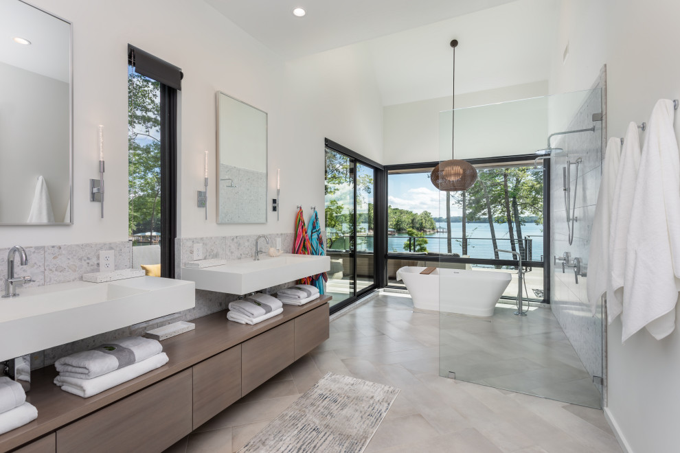 Design ideas for a large contemporary master wet room bathroom in Other with flat-panel cabinets, brown cabinets, a freestanding tub, a one-piece toilet, porcelain tile, white walls, porcelain floors, an integrated sink, beige floor, an open shower, white benchtops, a double vanity, a floating vanity and vaulted.