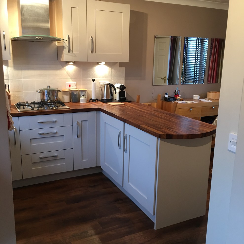 Small modern u-shaped eat-in kitchen in West Midlands with wood benchtops, stainless steel appliances and vinyl floors.