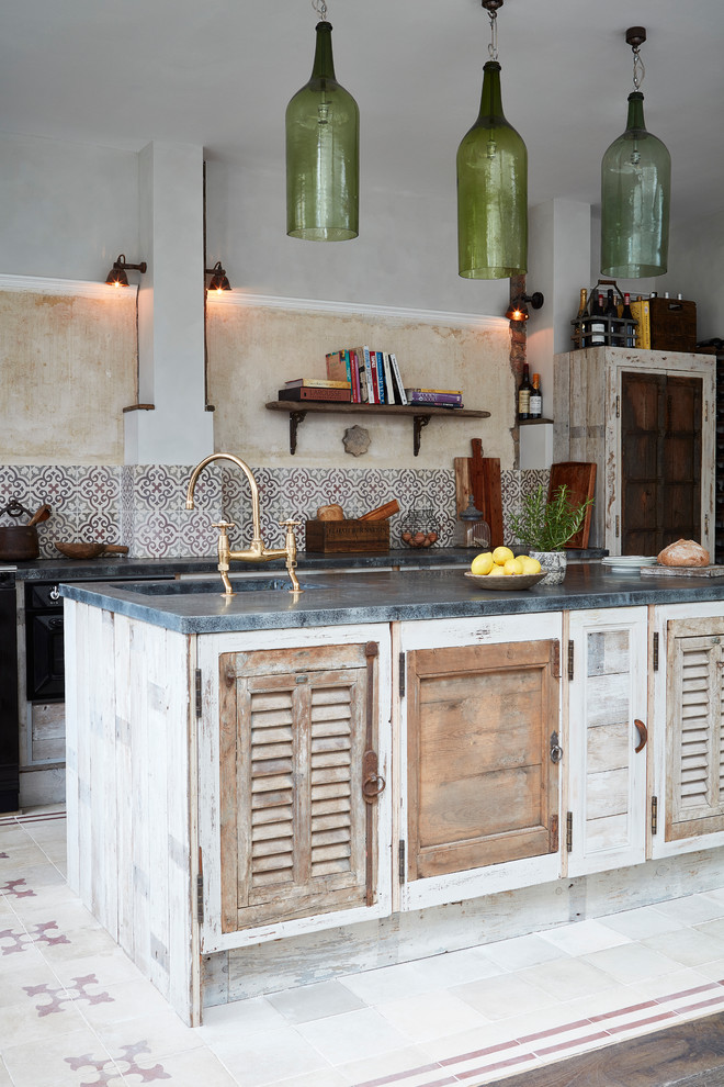 Mid-sized mediterranean single-wall kitchen in London with an undermount sink, louvered cabinets, distressed cabinets, cement tile splashback, cement tiles, with island and multi-coloured splashback.