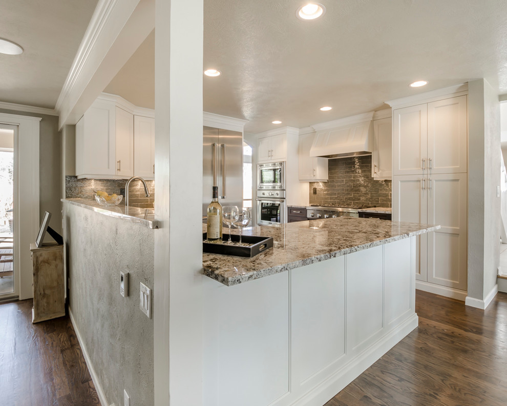 Mid-sized transitional u-shaped medium tone wood floor eat-in kitchen photo in Denver with a farmhouse sink, shaker cabinets, white cabinets, laminate countertops, green backsplash, glass tile backsplash, stainless steel appliances and a peninsula