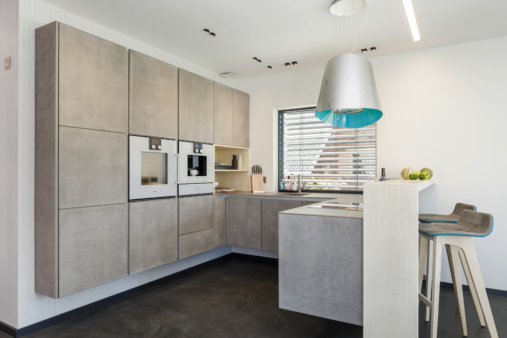 This is an example of a small contemporary u-shaped open plan kitchen in Munich with a drop-in sink, flat-panel cabinets, grey cabinets, panelled appliances and a peninsula.