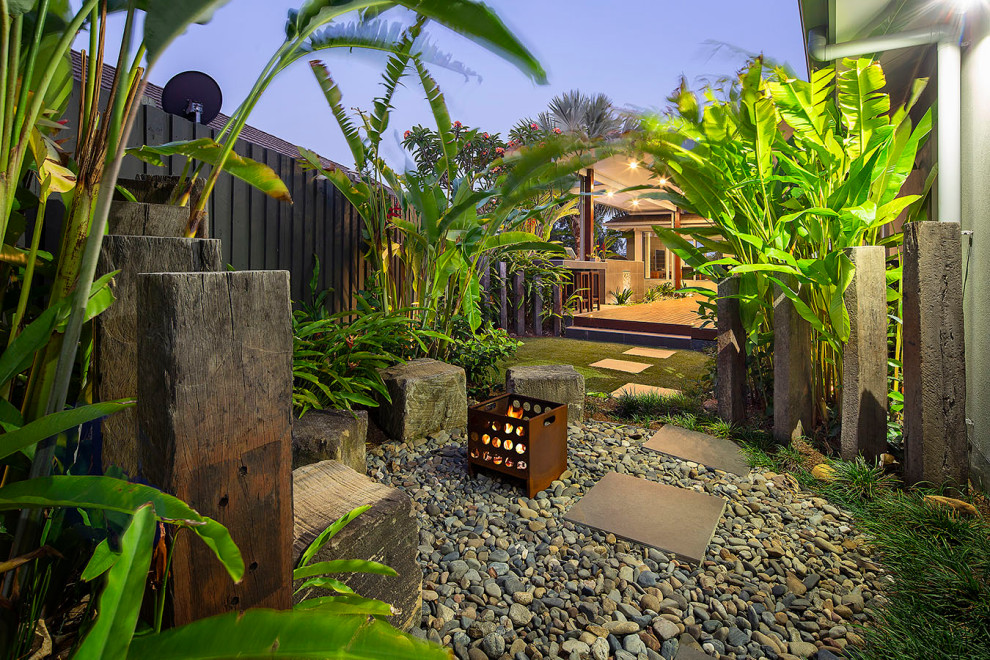 Réalisation d'un jardin arrière ethnique avec un foyer extérieur, une exposition partiellement ombragée, une terrasse en bois et une clôture en bois.