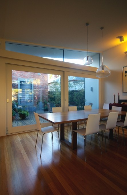 Photo of a mid-sized contemporary kitchen/dining combo in Melbourne with white walls and medium hardwood floors.