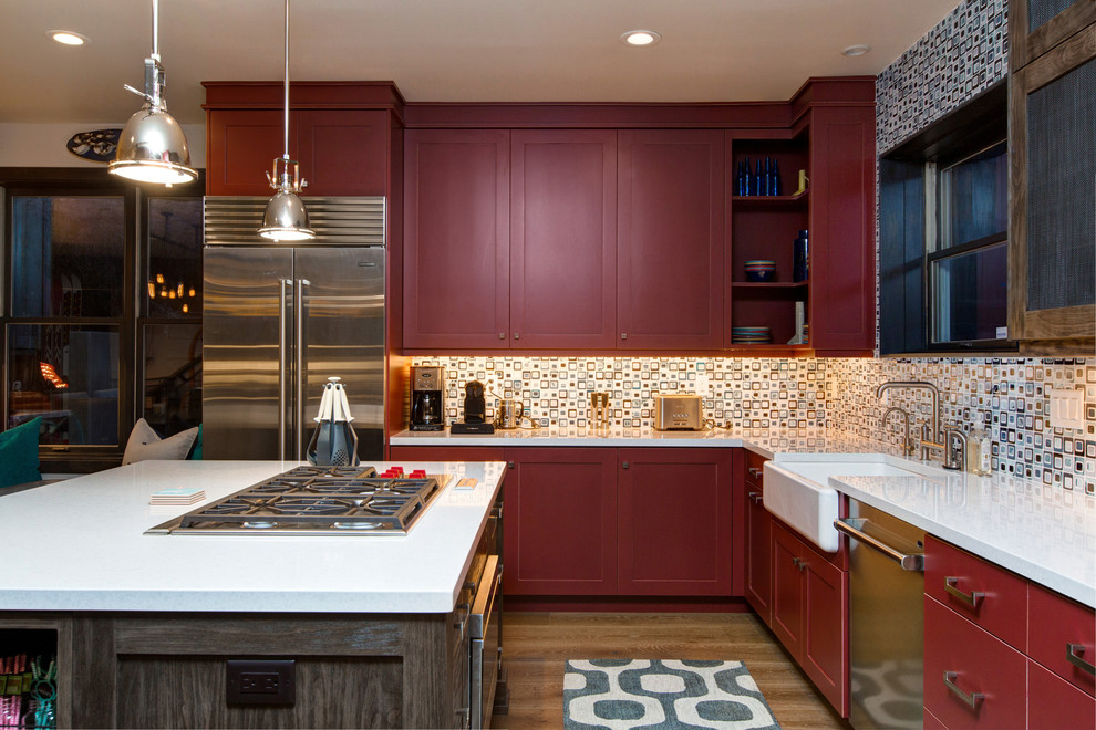 Design ideas for a mid-sized transitional l-shaped kitchen in Salt Lake City with a farmhouse sink, quartzite benchtops, stainless steel appliances, medium hardwood floors, with island, shaker cabinets, red cabinets, multi-coloured splashback, glass tile splashback and brown floor.