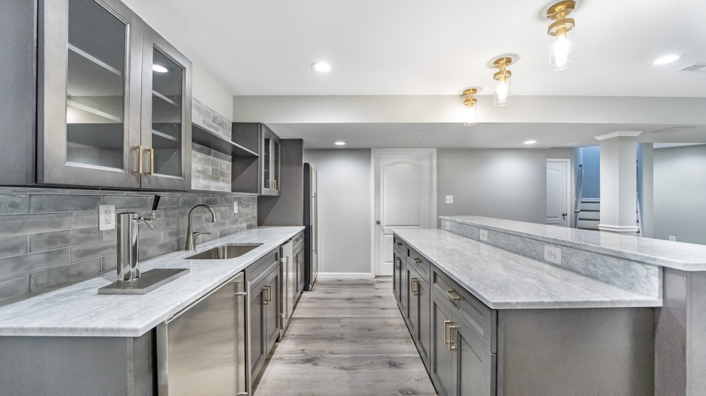Inspiration for a small transitional galley wet bar in DC Metro with an undermount sink, raised-panel cabinets, grey cabinets, granite benchtops, grey splashback, subway tile splashback, vinyl floors, grey floor and grey benchtop.