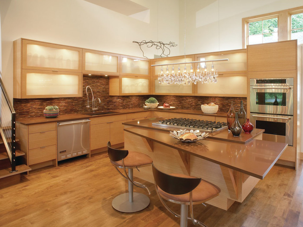 Photo of a large contemporary l-shaped open plan kitchen in Other with an undermount sink, light wood cabinets, quartz benchtops, stainless steel appliances, light hardwood floors, with island, glass-front cabinets, beige floor and brown benchtop.