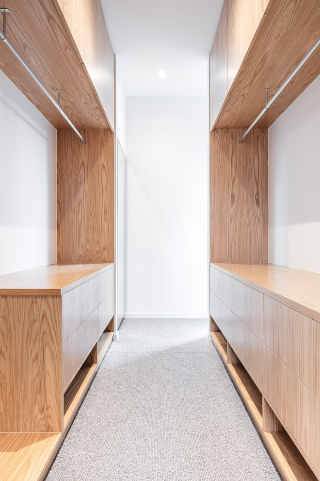 This is an example of a large contemporary gender-neutral walk-in wardrobe in Melbourne with open cabinets, light wood cabinets, carpet and beige floor.