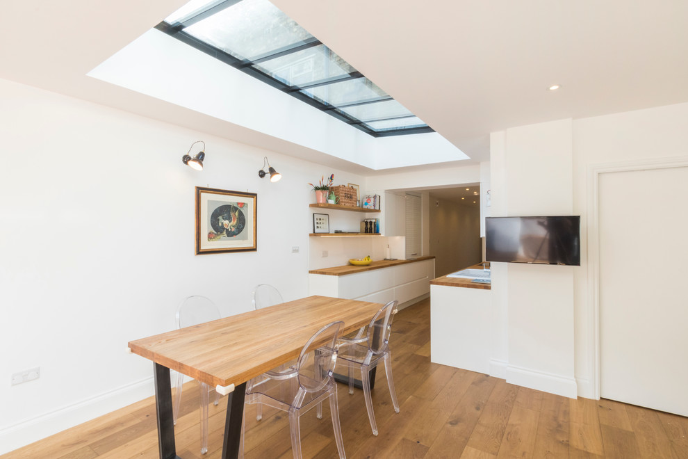 Design ideas for a contemporary kitchen in London with white cabinets and wood benchtops.
