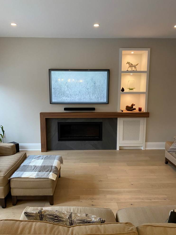 This is an example of a large contemporary open plan games room in Toronto with grey walls, light hardwood flooring, a tiled fireplace surround, a wall mounted tv and beige floors.