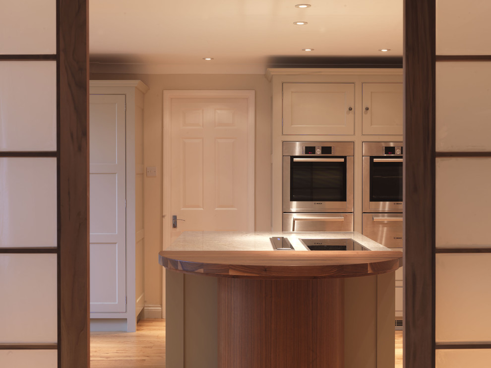 Design ideas for a mid-sized traditional l-shaped open plan kitchen in Hampshire with shaker cabinets, beige cabinets, granite benchtops, beige splashback, stainless steel appliances and with island.