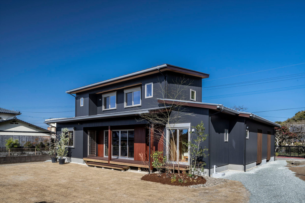 Идея дизайна: двухэтажный, черный частный загородный дом в стиле модернизм с облицовкой из металла, односкатной крышей, металлической крышей, серой крышей и отделкой доской с нащельником
