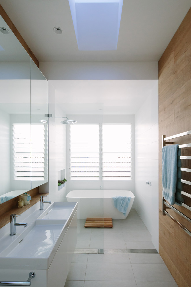 Photo of a mid-sized contemporary master bathroom in Sydney with flat-panel cabinets, white cabinets, a freestanding tub, an open shower, white tile, white walls, an integrated sink, white floor and an open shower.