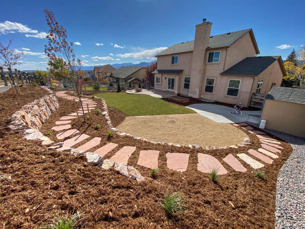 Inspiration for a large traditional sloped xeriscape full sun garden for autumn in Denver with a retaining wall, concrete paving and a wood fence.