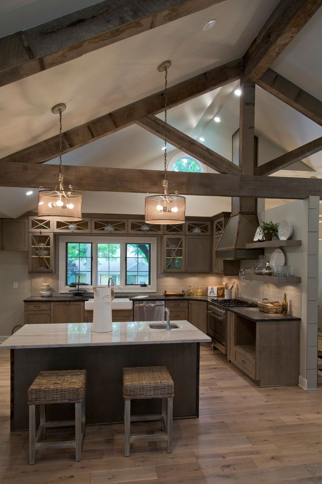 Design ideas for a large country l-shaped open plan kitchen in Kansas City with a farmhouse sink, glass-front cabinets, medium wood cabinets, granite benchtops, beige splashback, stainless steel appliances, medium hardwood floors, with island and brown floor.