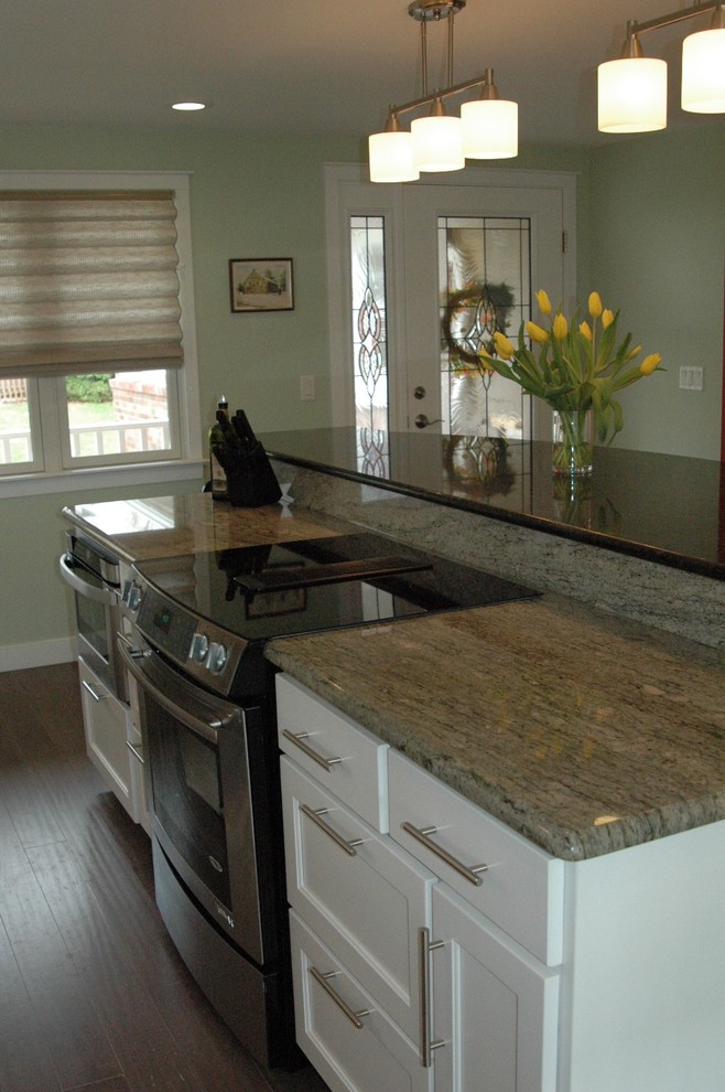 Mid-sized transitional l-shaped medium tone wood floor and brown floor enclosed kitchen photo in Boston with an undermount sink, recessed-panel cabinets, white cabinets, granite countertops, multicolored backsplash, glass tile backsplash, stainless steel appliances and an island