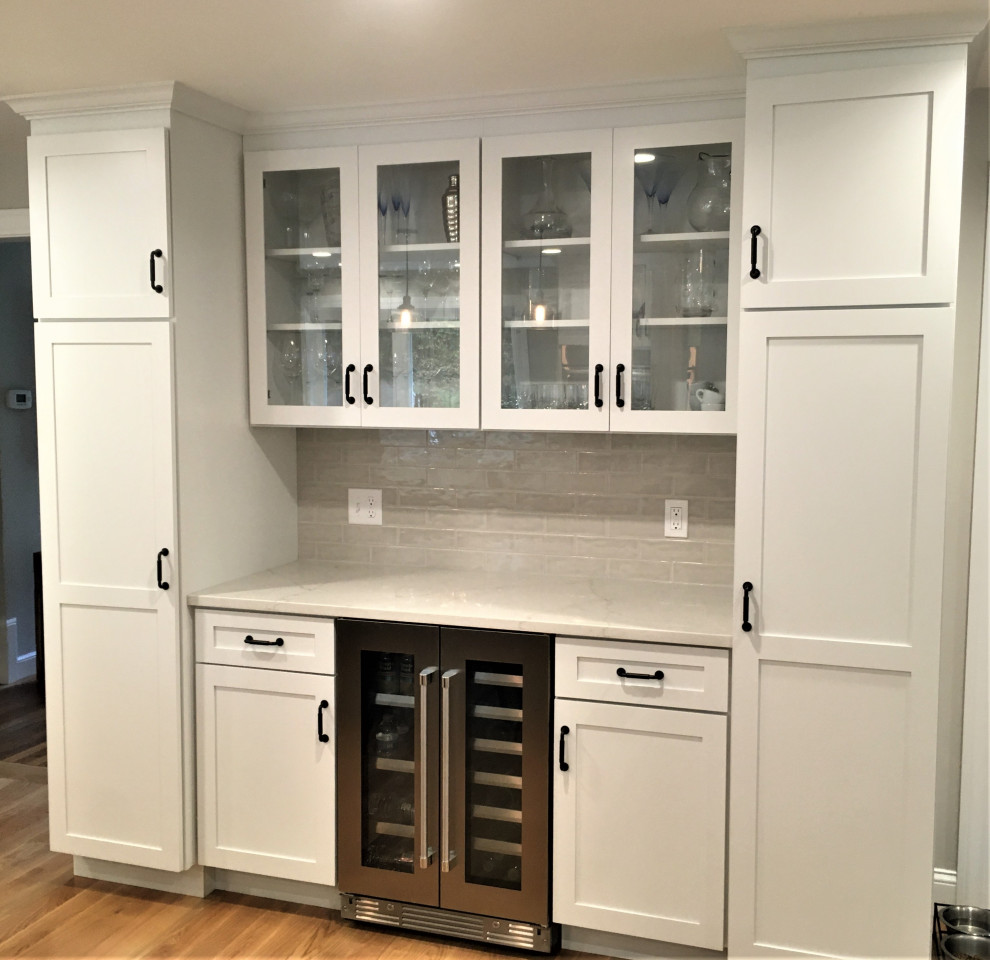 Large transitional u-shaped light wood floor and brown floor eat-in kitchen photo in Boston with a farmhouse sink, shaker cabinets, white cabinets, quartz countertops, beige backsplash, subway tile backsplash, stainless steel appliances, an island and white countertops