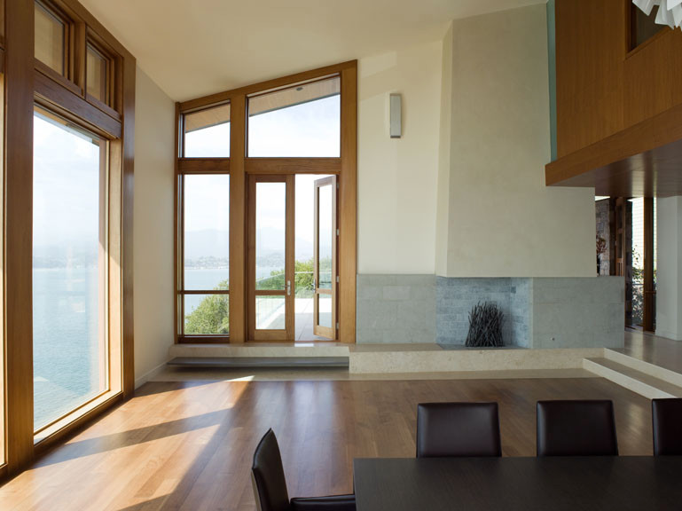 Cette image montre un très grand salon minimaliste ouvert avec un mur blanc, un sol en bois brun, une cheminée standard et un manteau de cheminée en pierre.