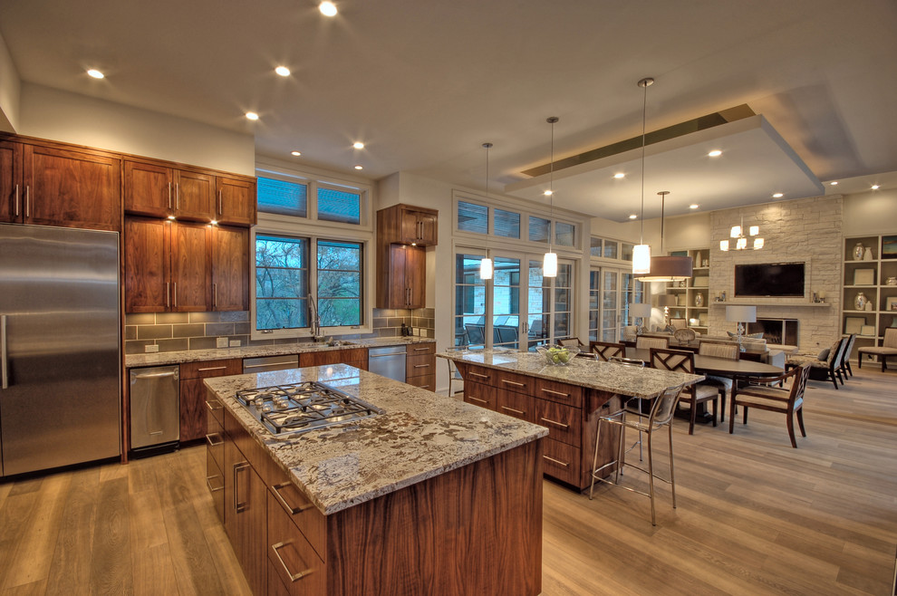 This is an example of a transitional open plan kitchen in Austin with recessed-panel cabinets, dark wood cabinets and stainless steel appliances.