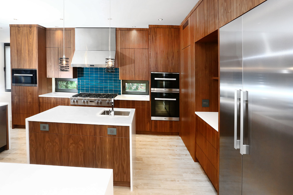 This is an example of an expansive asian l-shaped eat-in kitchen in Vancouver with a drop-in sink, flat-panel cabinets, light wood cabinets, quartz benchtops, blue splashback, glass tile splashback, stainless steel appliances, bamboo floors, multiple islands and grey floor.