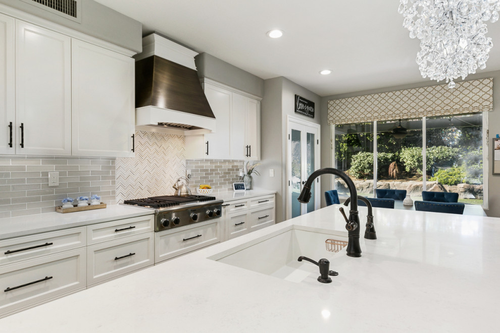 Inspiration for a huge transitional u-shaped travertine floor and beige floor open concept kitchen remodel in Orange County with a single-bowl sink, shaker cabinets, white cabinets, quartz countertops, multicolored backsplash, stone tile backsplash, stainless steel appliances, an island and white countertops