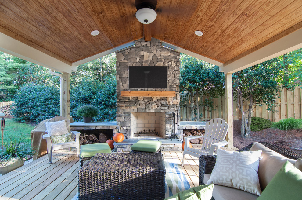 This is an example of a large country backyard deck in Other with a fire feature and a roof extension.