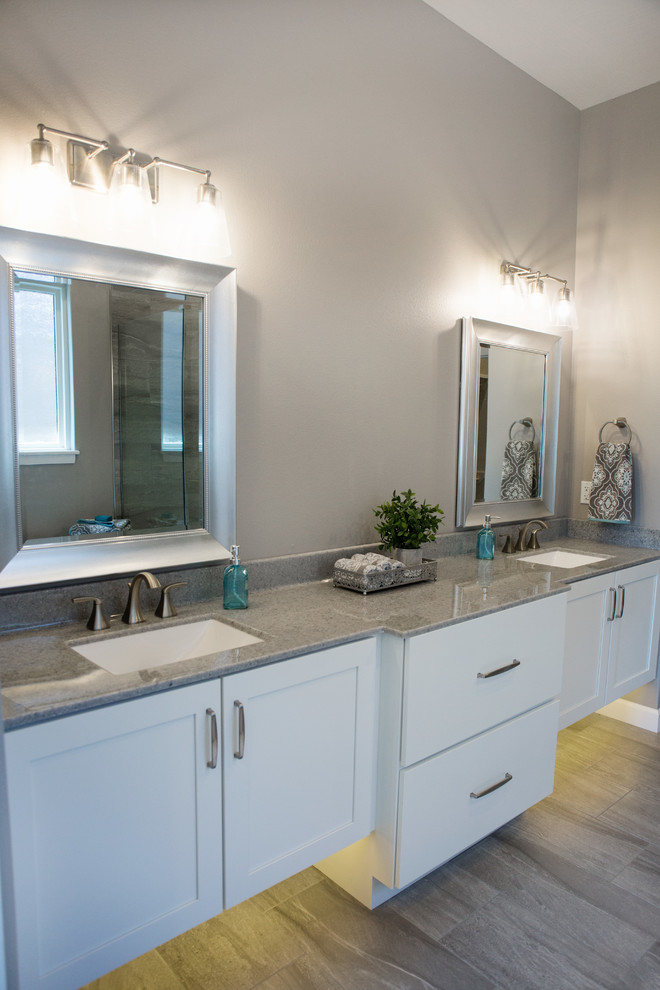 Large transitional master gray tile and porcelain tile porcelain tile and gray floor freestanding bathtub photo with flat-panel cabinets, white cabinets, gray walls, an integrated sink, solid surface countertops and gray countertops