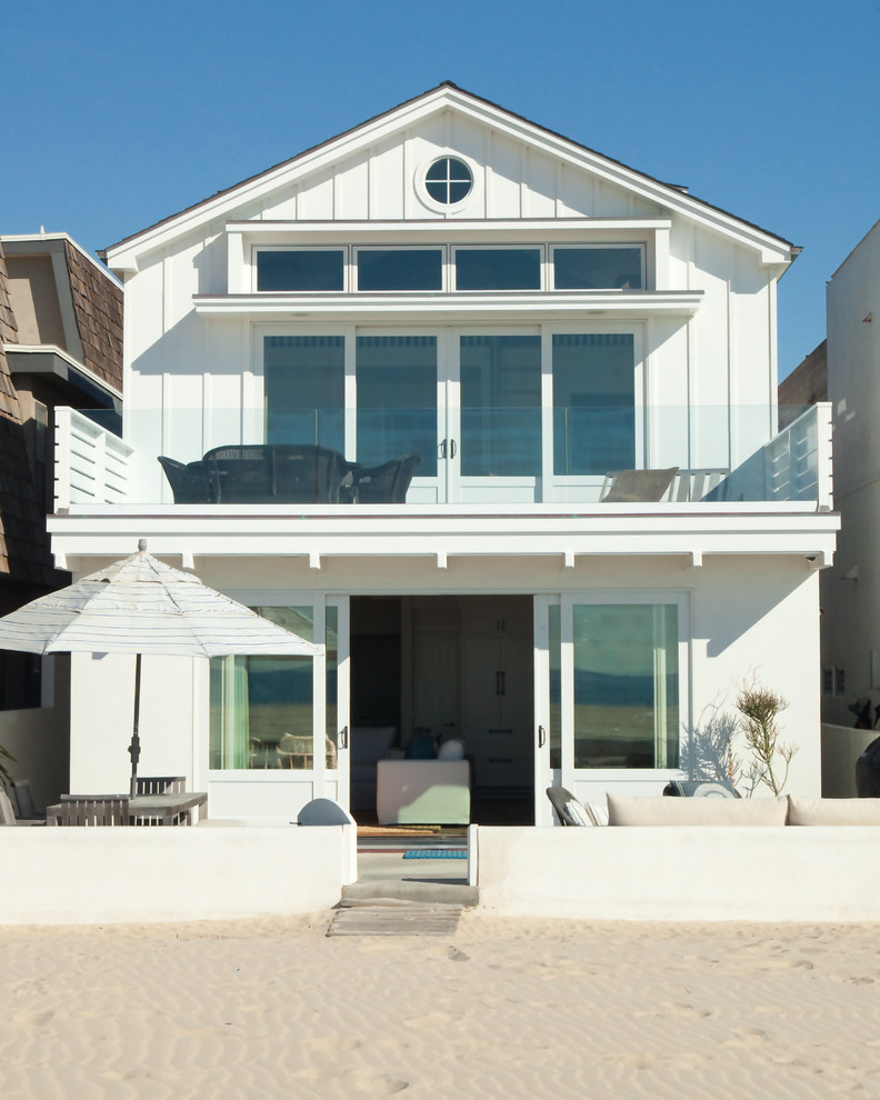 This is an example of a small beach style two-storey white exterior in Orange County with a gable roof and vinyl siding.