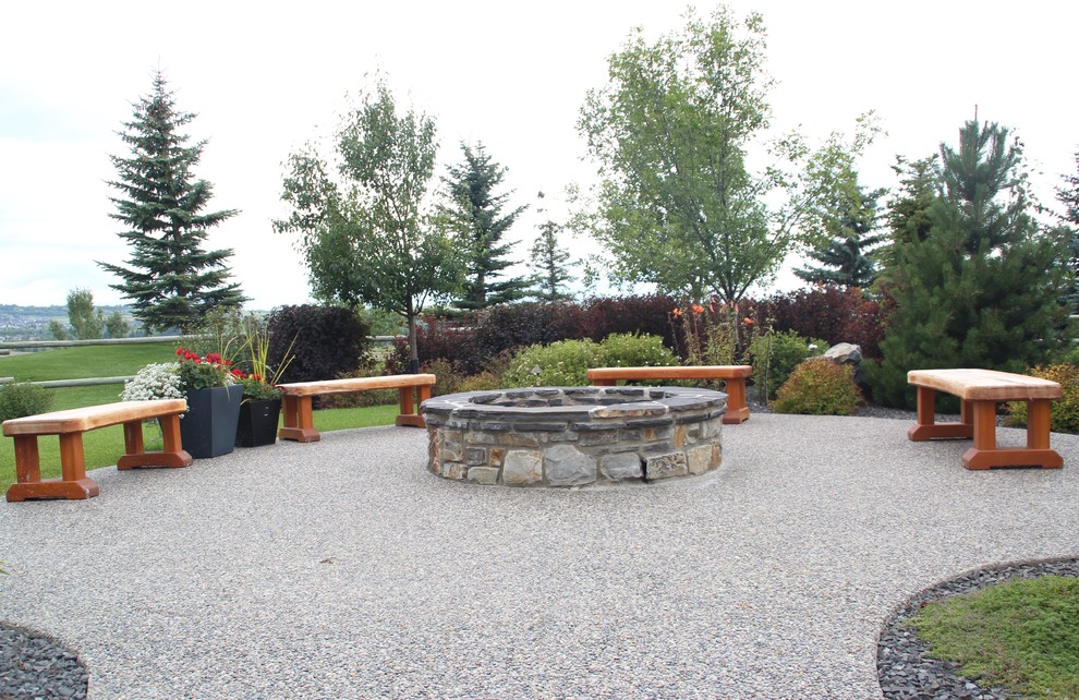 This is an example of a large country backyard partial sun garden in Calgary with with pond and natural stone pavers.