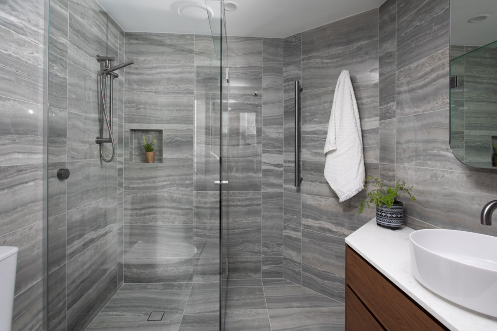 Small contemporary bathroom in Brisbane with medium wood cabinets, a one-piece toilet, gray tile, porcelain tile, grey walls, porcelain floors, a vessel sink, grey floor, a hinged shower door, white benchtops, a niche, a single vanity and a floating vanity.