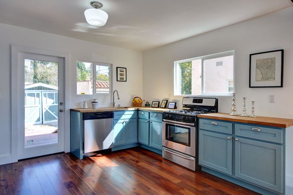 Photo of a small contemporary l-shaped eat-in kitchen in Los Angeles with an undermount sink, shaker cabinets, turquoise cabinets, wood benchtops, stainless steel appliances and medium hardwood floors.