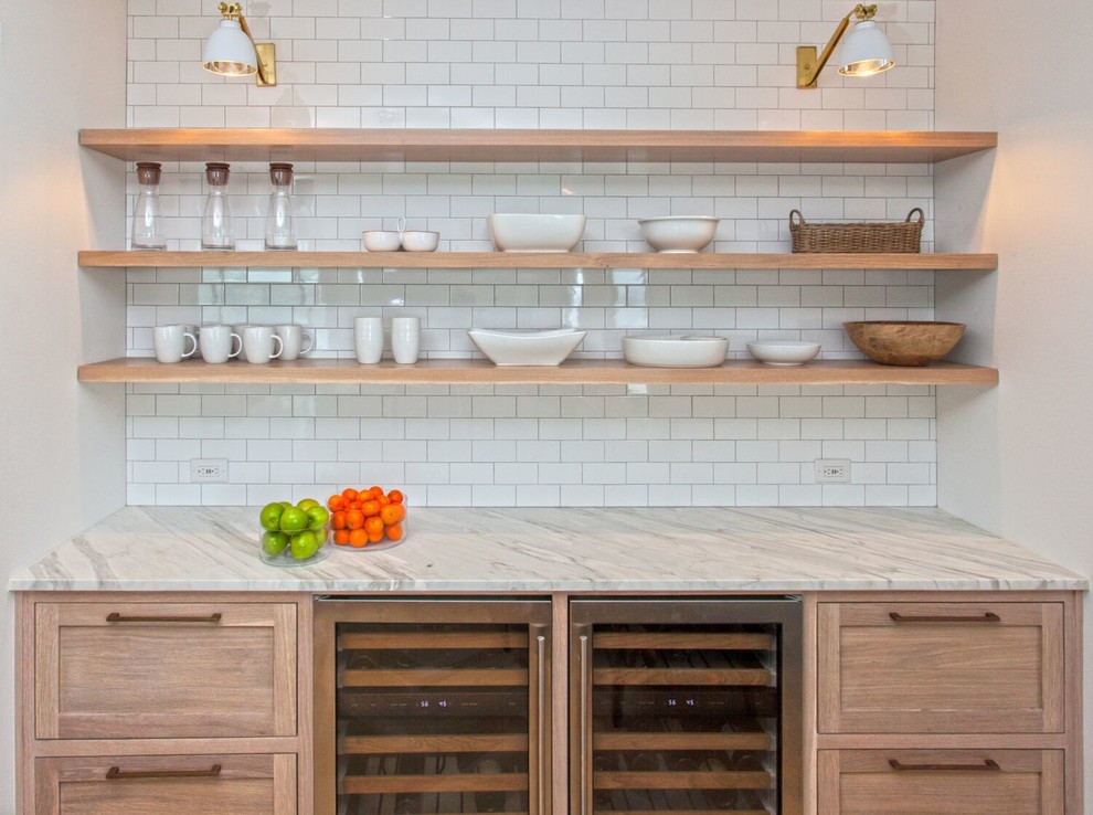 Inspiration for a mid-sized transitional single-wall wet bar in Charlotte with no sink, shaker cabinets, light wood cabinets, marble benchtops, white splashback, subway tile splashback, light hardwood floors and white benchtop.
