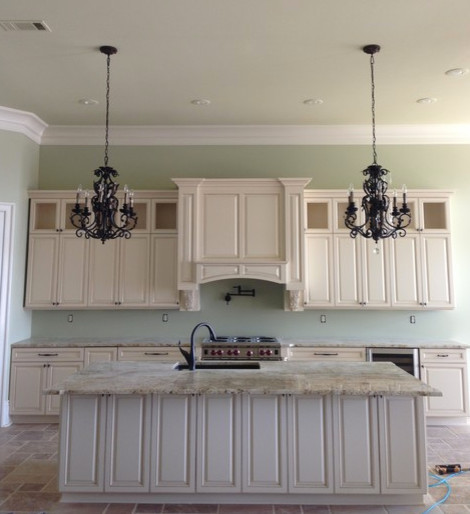 This is an example of a large mediterranean l-shaped open plan kitchen in New Orleans with an undermount sink, raised-panel cabinets, beige cabinets, granite benchtops, beige splashback, panelled appliances, travertine floors and with island.