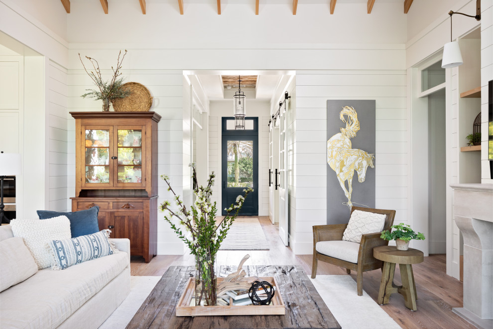 Design ideas for a beach style open concept living room in Tampa with white walls, light hardwood floors, a standard fireplace, a stone fireplace surround, a wall-mounted tv, brown floor, exposed beam and planked wall panelling.