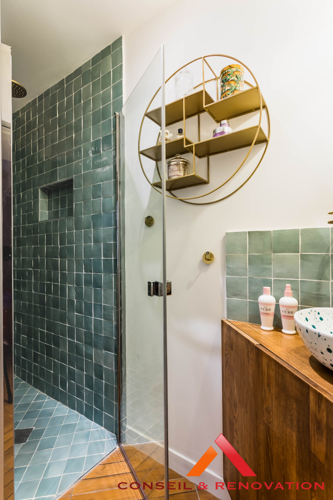 This is an example of a small contemporary bathroom in Paris with beaded inset cabinets, dark wood cabinets, an alcove shower, green tile, terra-cotta tile, green walls, wood-look tile, a drop-in sink, wood benchtops, brown floor, a hinged shower door, blue benchtops, a single vanity and a built-in vanity.