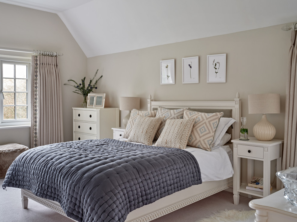 This is an example of a mid-sized transitional master bedroom in Hertfordshire with beige walls, carpet, beige floor and vaulted.