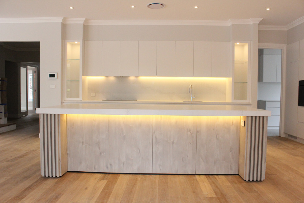 Inspiration for a large modern kitchen/diner in Sydney with a submerged sink, white cabinets, engineered stone countertops, white splashback, stone slab splashback, integrated appliances, an island and white worktops.