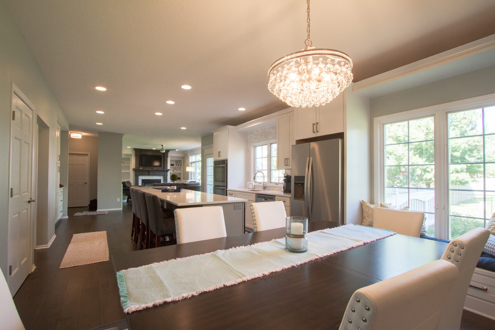 Example of a transitional single-wall dark wood floor and brown floor open concept kitchen design with an undermount sink, recessed-panel cabinets, white cabinets, quartzite countertops, gray backsplash, marble backsplash, stainless steel appliances and an island