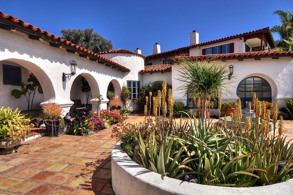 This is an example of an expansive mediterranean courtyard patio in Orange County with a water feature, tile and no cover.