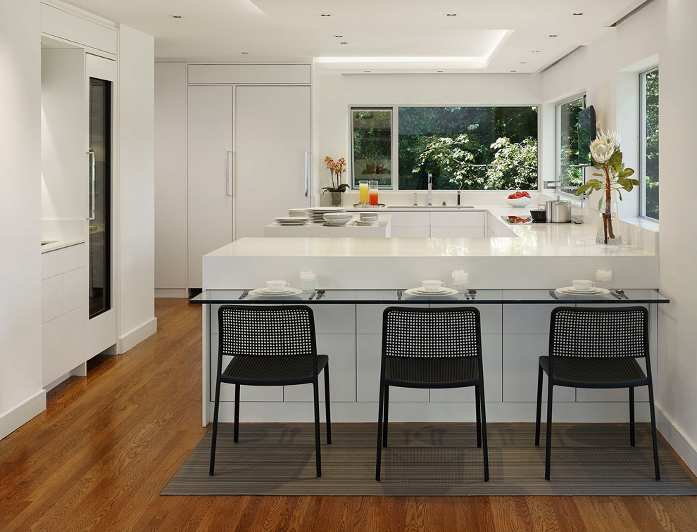 Photo of a large modern u-shaped eat-in kitchen in San Francisco with an undermount sink, flat-panel cabinets, white cabinets, panelled appliances, medium hardwood floors, with island, white splashback, quartz benchtops and brown floor.